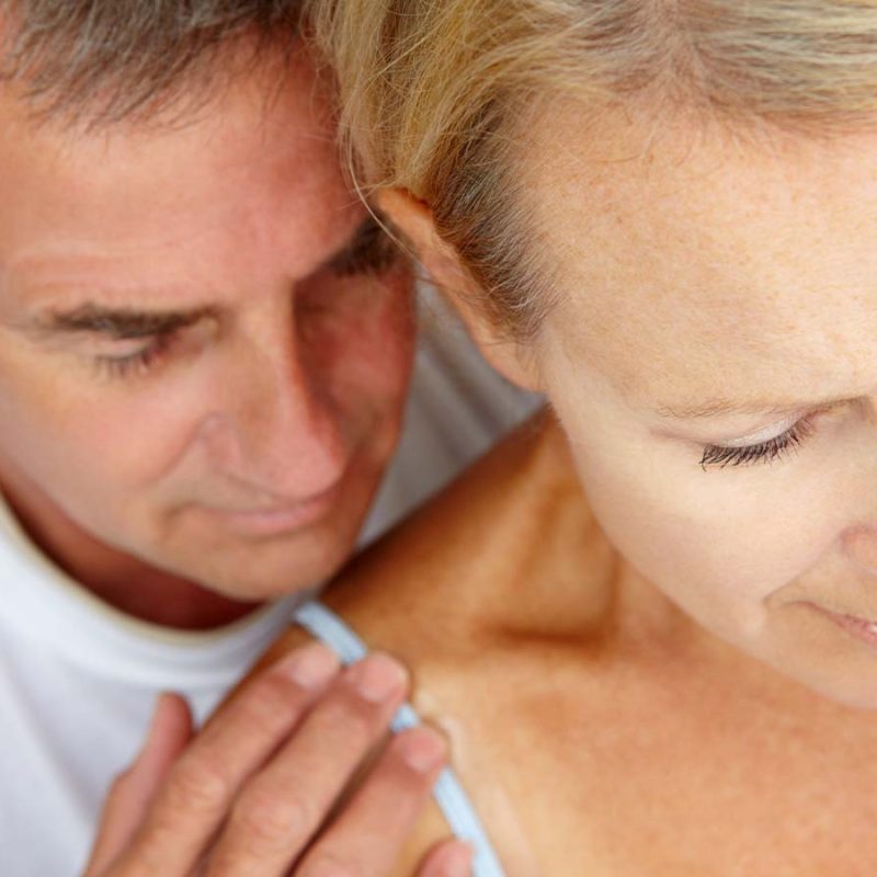 A man holding his partner's shoulder concerned about her.